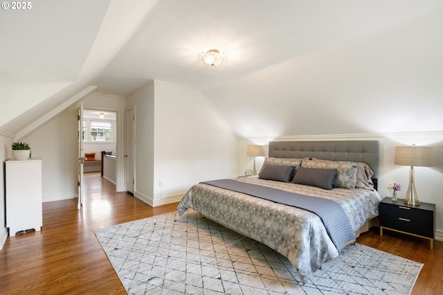 bedroom featuring wood finished floors, lofted ceiling, and baseboards