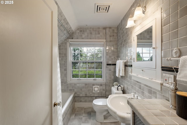 full bath featuring tile walls, a sink, tile patterned flooring, a tub, and toilet