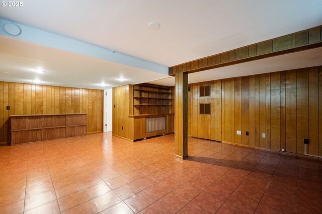 finished basement featuring wooden walls, a bar, and built in shelves