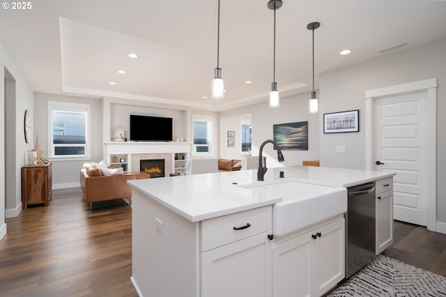 kitchen with sink, black dishwasher, white cabinets, hanging light fixtures, and a center island with sink