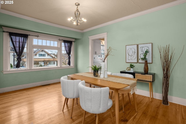 dining room featuring baseboards, wood finished floors, a notable chandelier, and ornamental molding