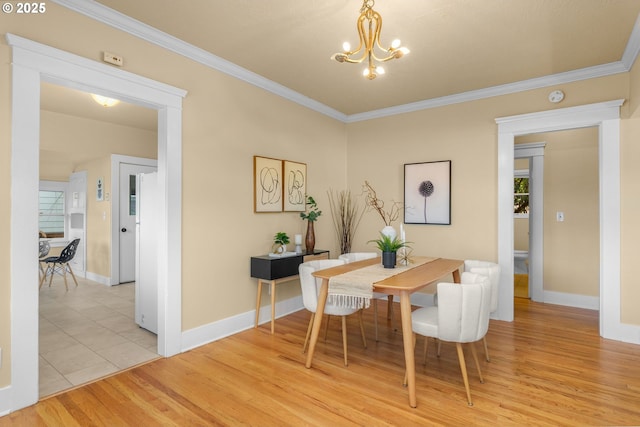 dining room with crown molding, baseboards, light wood finished floors, and a chandelier
