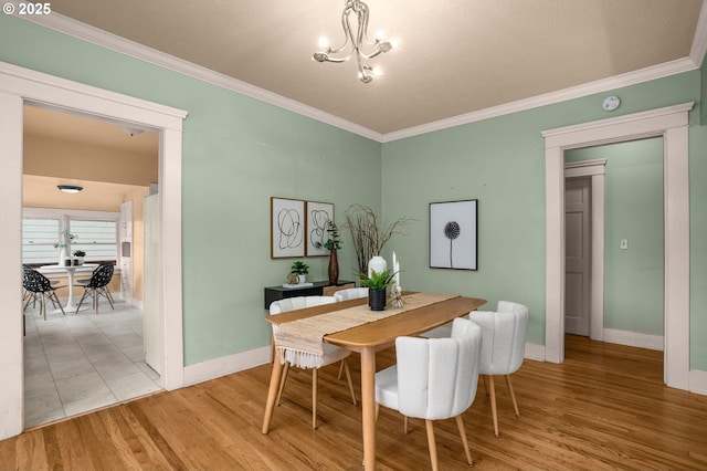 dining space with a chandelier, ornamental molding, and wood finished floors