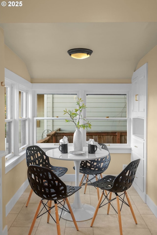 tiled dining area with baseboards and vaulted ceiling