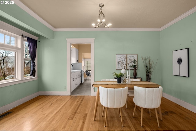 dining area featuring a notable chandelier, visible vents, light wood-type flooring, and ornamental molding