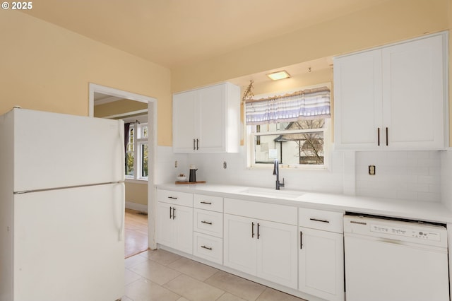 kitchen with white appliances, a sink, light countertops, white cabinetry, and backsplash