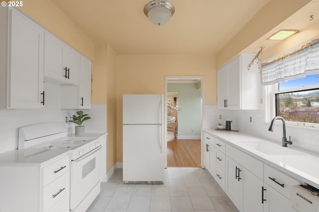 kitchen featuring white appliances, white cabinets, light countertops, and a sink