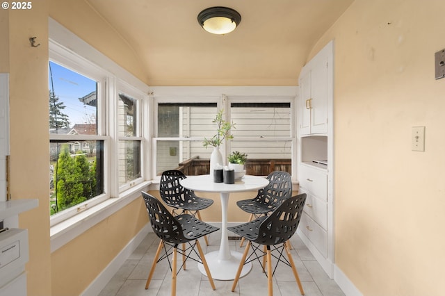 dining space featuring vaulted ceiling, plenty of natural light, baseboards, and light tile patterned floors