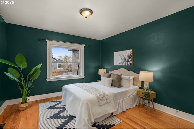 bedroom with visible vents, baseboards, and wood finished floors