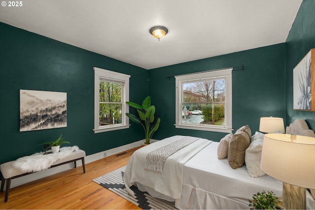 bedroom featuring wood finished floors, visible vents, and baseboards