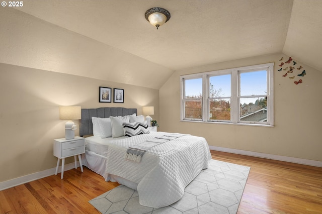 bedroom featuring baseboards, lofted ceiling, and wood finished floors