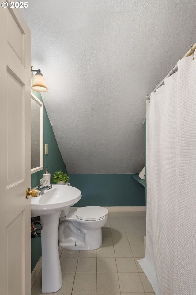 bathroom with baseboards, vaulted ceiling, a textured ceiling, tile patterned floors, and toilet