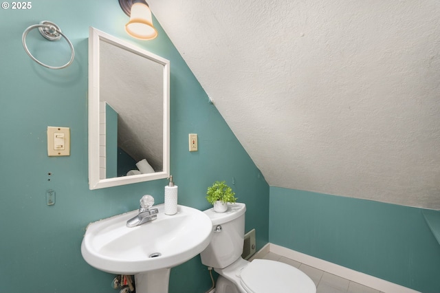 half bath featuring baseboards, a sink, vaulted ceiling, a textured ceiling, and toilet