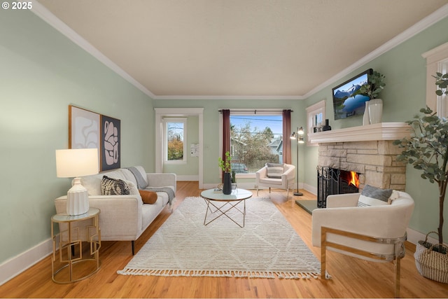 living area featuring a stone fireplace, ornamental molding, baseboards, and wood finished floors