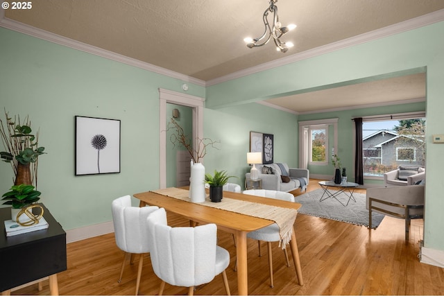 dining space featuring light wood-type flooring, baseboards, a chandelier, and ornamental molding