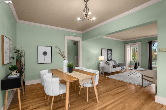 dining area featuring ornamental molding, baseboards, light wood-type flooring, and a chandelier