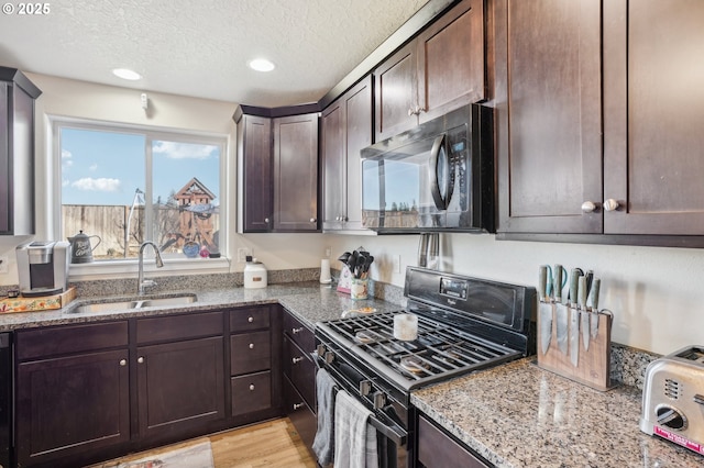 kitchen featuring dark brown cabinetry, sink, black appliances, and light stone countertops