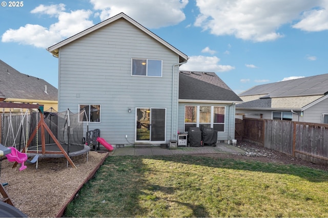 back of house with a trampoline, a yard, and a patio area