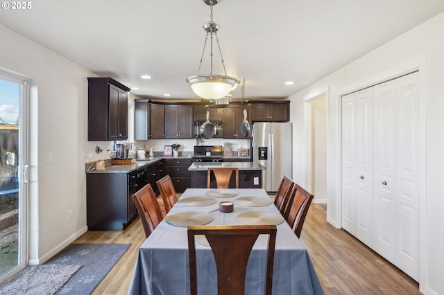 kitchen with dark brown cabinets, pendant lighting, light hardwood / wood-style floors, and black appliances