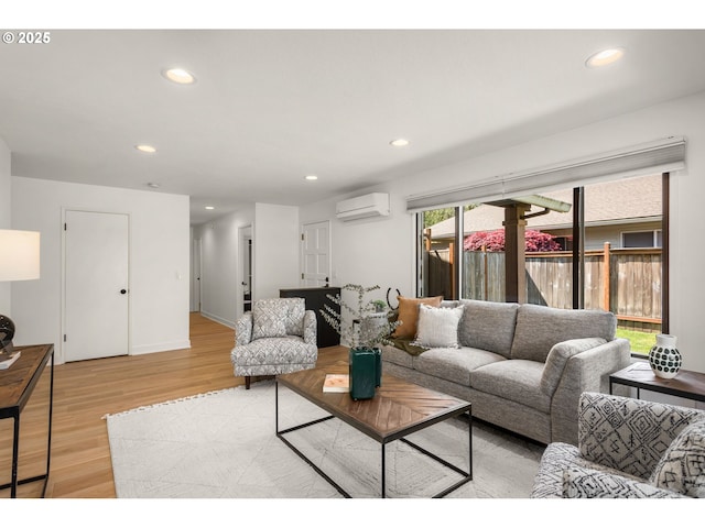 living room featuring recessed lighting, baseboards, a wall unit AC, and light wood finished floors