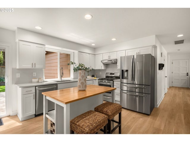 kitchen with wooden counters, visible vents, appliances with stainless steel finishes, a sink, and under cabinet range hood