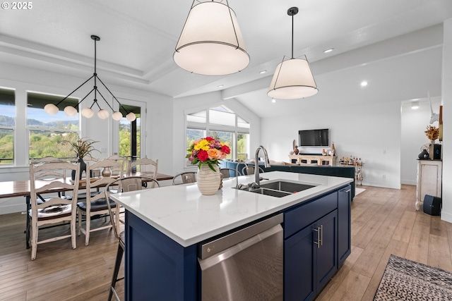 kitchen featuring stainless steel dishwasher, light countertops, blue cabinets, a sink, and light wood finished floors