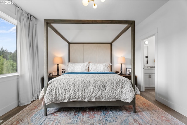 bedroom featuring baseboards, ensuite bath, and wood finished floors