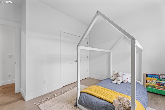 bedroom with baseboards, wood finished floors, and a closet
