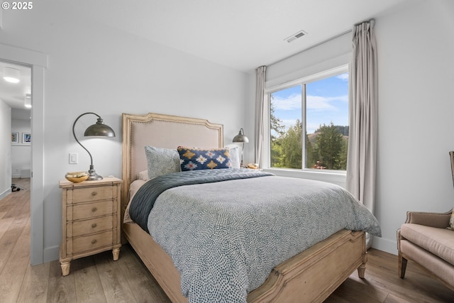 bedroom featuring visible vents, baseboards, and wood finished floors