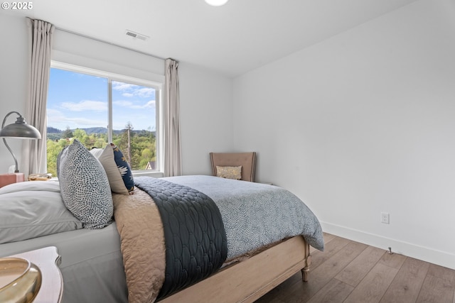 bedroom with visible vents, baseboards, a mountain view, and hardwood / wood-style flooring