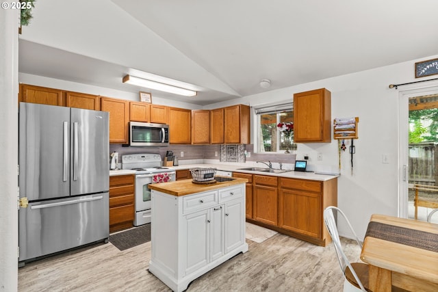 3318 Pinyon St, Springfield, OR 97478 - kitchen with appliances with stainless steel finishes, vaulted ceiling, a sink, light wood-type flooring, and tasteful backsplash