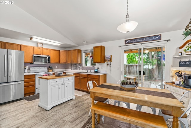 3318 Pinyon St, Springfield, OR 97478 - kitchen featuring appliances with stainless steel finishes, light countertops, brown cabinets, lofted ceiling, and light wood finished floors