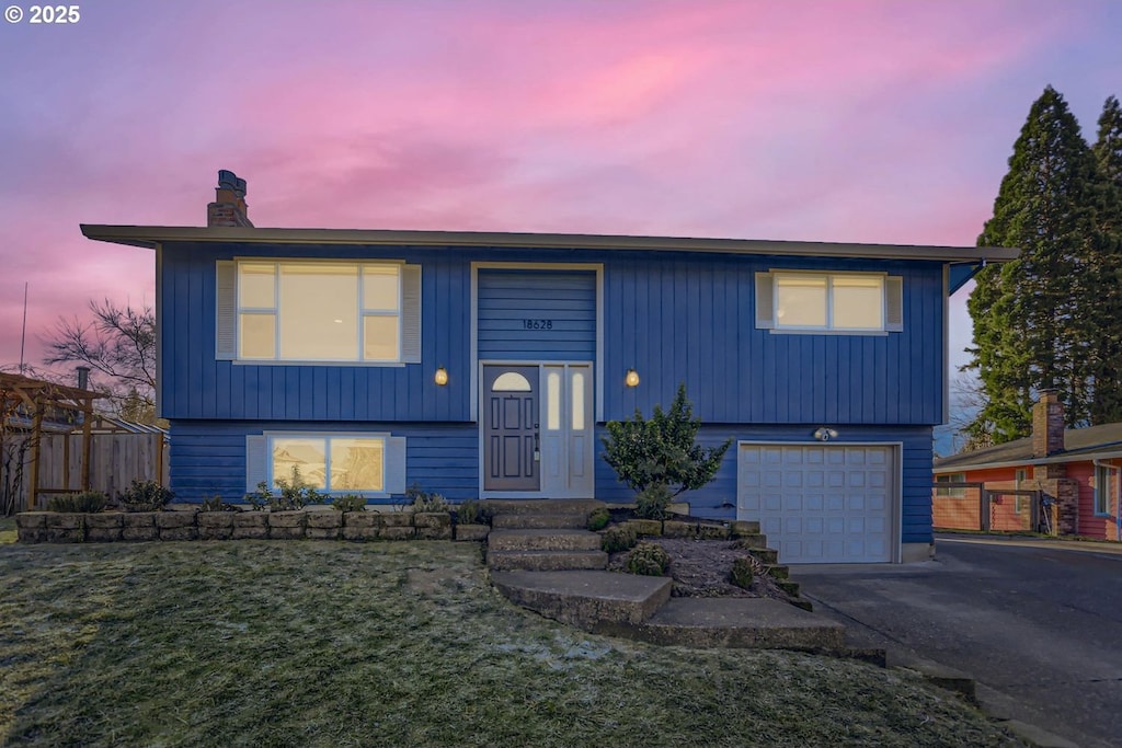 split foyer home featuring a garage and a lawn