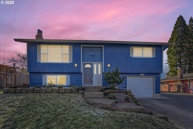 split foyer home featuring a garage and a lawn