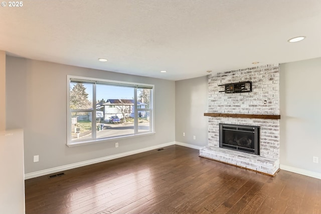 unfurnished living room with a brick fireplace and dark wood-type flooring