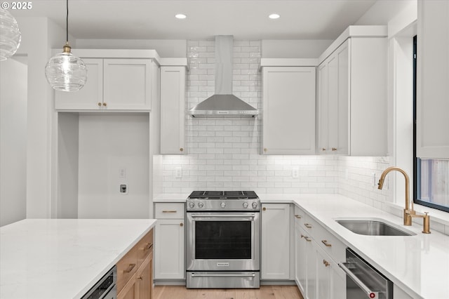 kitchen featuring light stone countertops, white cabinets, wall chimney range hood, stainless steel appliances, and hanging light fixtures