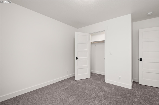 unfurnished bedroom with dark colored carpet and a closet