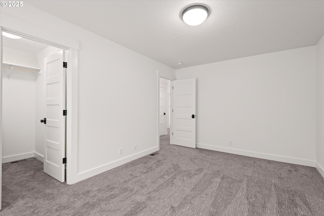 unfurnished bedroom with a closet, carpet, and a walk in closet