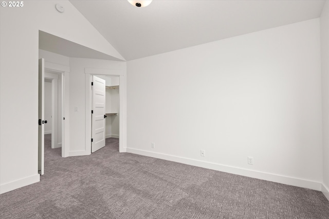 unfurnished bedroom featuring vaulted ceiling, a closet, a walk in closet, and carpet floors