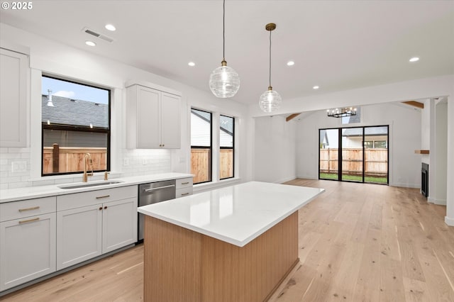 kitchen with sink, backsplash, a center island, and hanging light fixtures