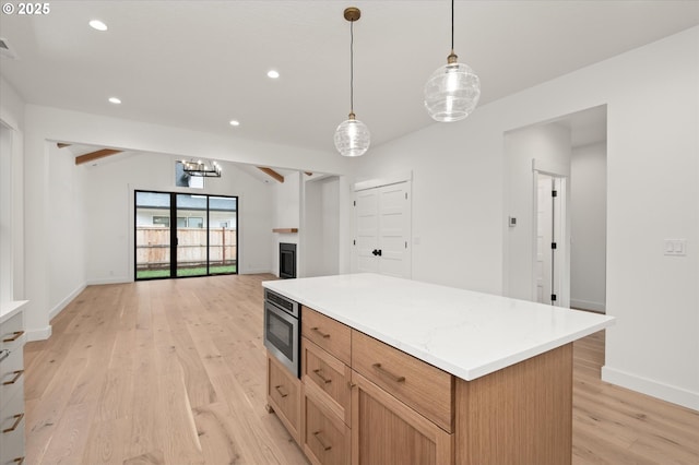 kitchen with stainless steel microwave, a center island, vaulted ceiling with beams, hanging light fixtures, and light wood-type flooring