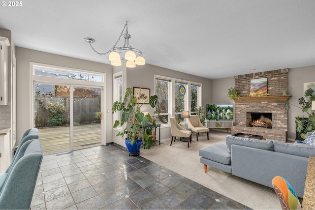 living room featuring dark colored carpet, a chandelier, a wealth of natural light, and a fireplace