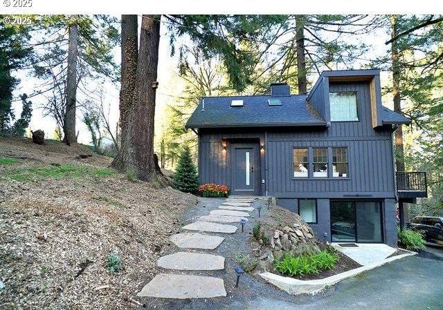 view of front facade featuring a shingled roof, board and batten siding, and a chimney