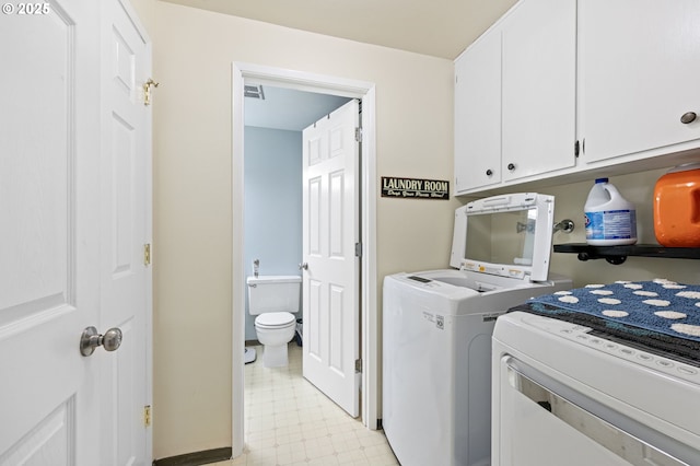 clothes washing area with visible vents, cabinet space, washer and dryer, and light floors