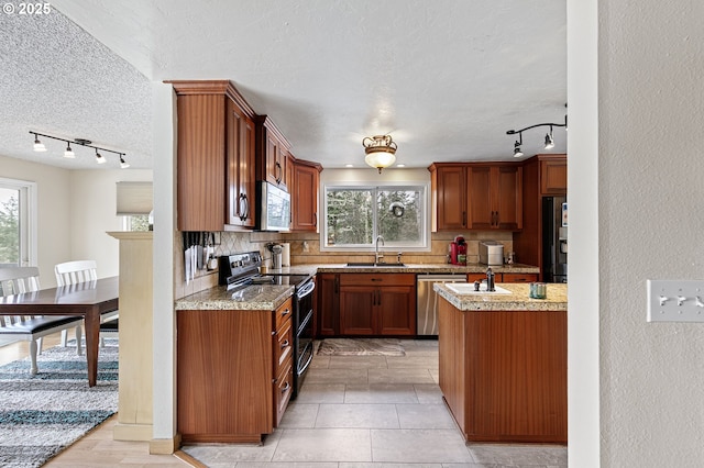 kitchen with light stone countertops, a sink, stainless steel appliances, a textured ceiling, and tasteful backsplash