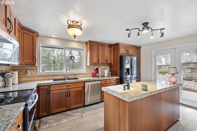 kitchen featuring a healthy amount of sunlight, brown cabinets, appliances with stainless steel finishes, and a sink