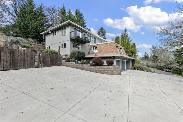 view of side of property featuring a balcony, fence, and driveway