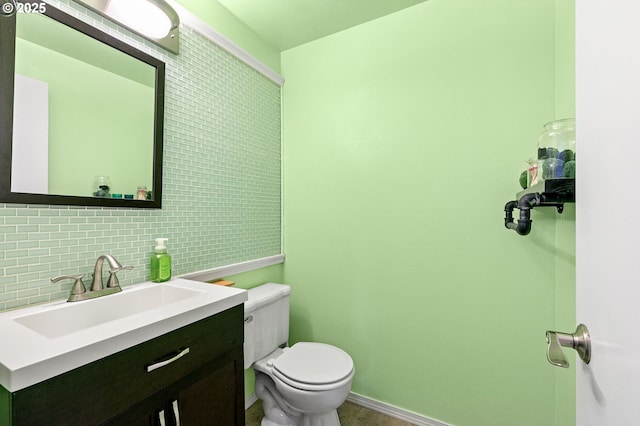 bathroom with vanity, decorative backsplash, toilet, and baseboards