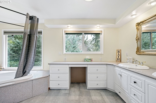 full bath with a wealth of natural light, vanity, a bathtub, and wood finished floors