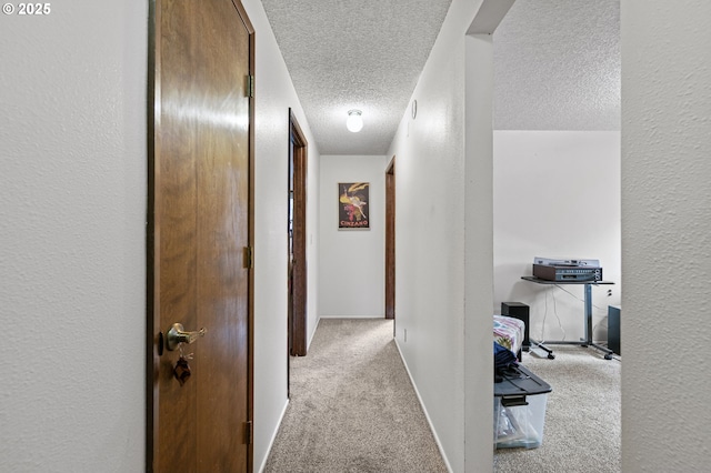 hall with carpet flooring, a textured ceiling, baseboards, and a textured wall